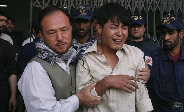 An ethnic Hazara Shi'ite man is comforted by his relative after he arrived at the local hospital in Quetta