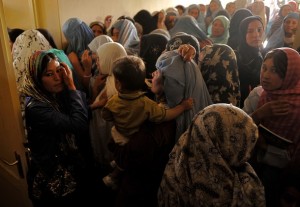 Afghan burqa-clad women watch as a polli